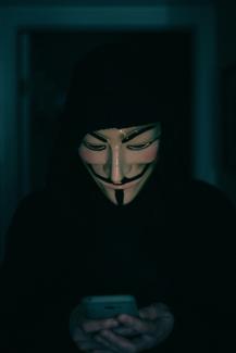 a person wearing a mask using a cell phone by Erik Mclean courtesy of Unsplash.